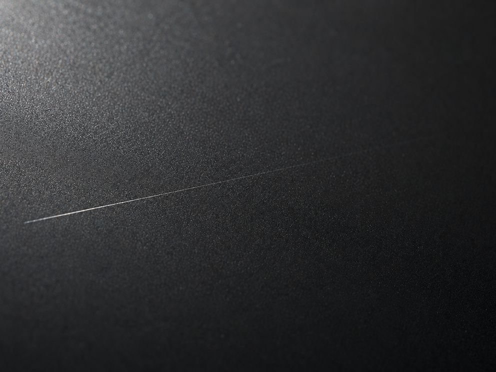 A fine scratch on a protected panel, half of it already closed